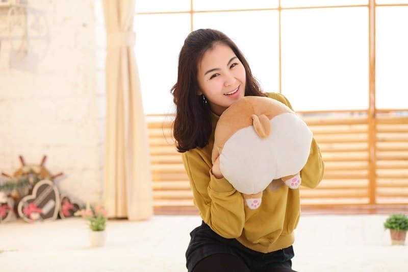 woman holding a corgi butt plush handwarmer