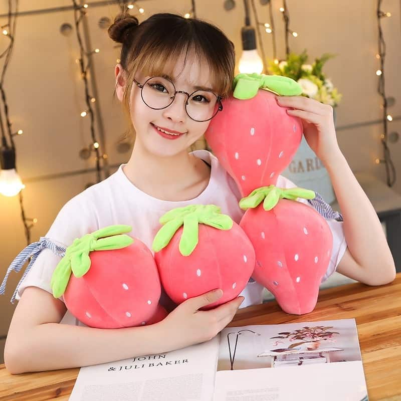 Woman holding 4 cute pink strawberry plushies