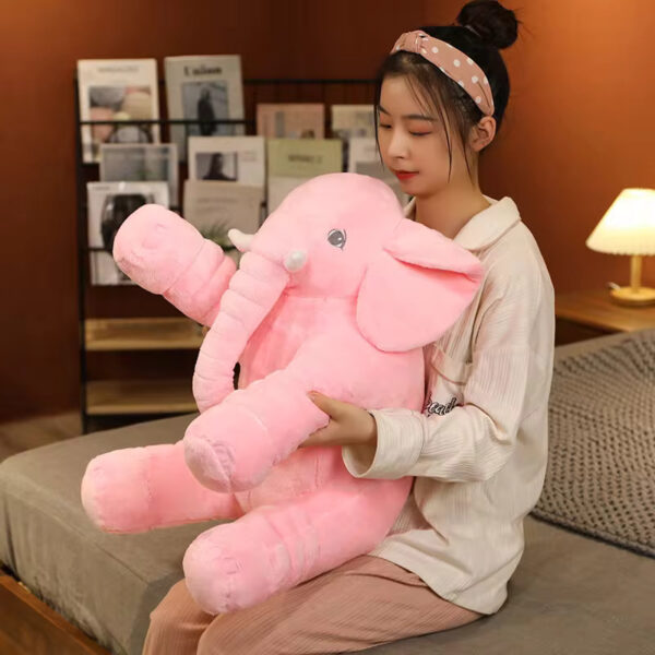 A woman hugging a pink baby elephant stuffed animal.