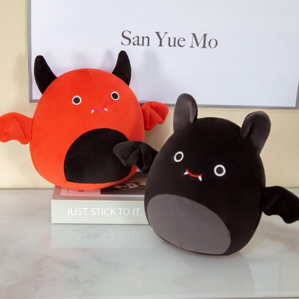 Red and Black Cute Bat Plush above a book