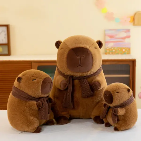 A group of three brown capybara plush toys in various sizes, all wearing matching knitted scarves, displayed on a white surface.