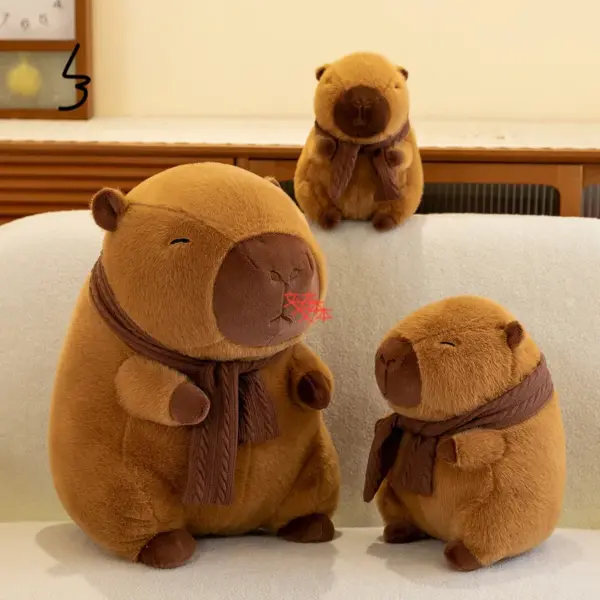 Three brown capybara plush toys of different sizes wearing knitted scarves, sitting together on a sofa.