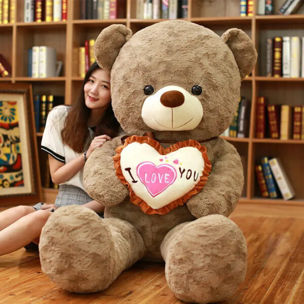 a woman sitting next to a large teddy bear