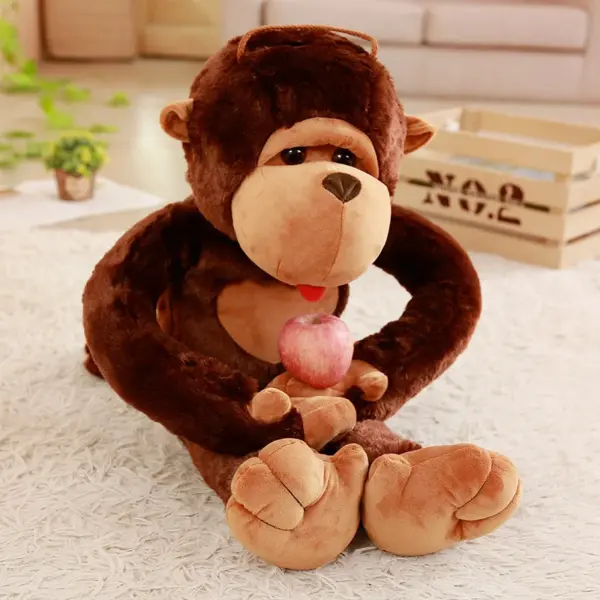Adorable monkey plush toy holding a red apple while sitting on a fluffy white rug.